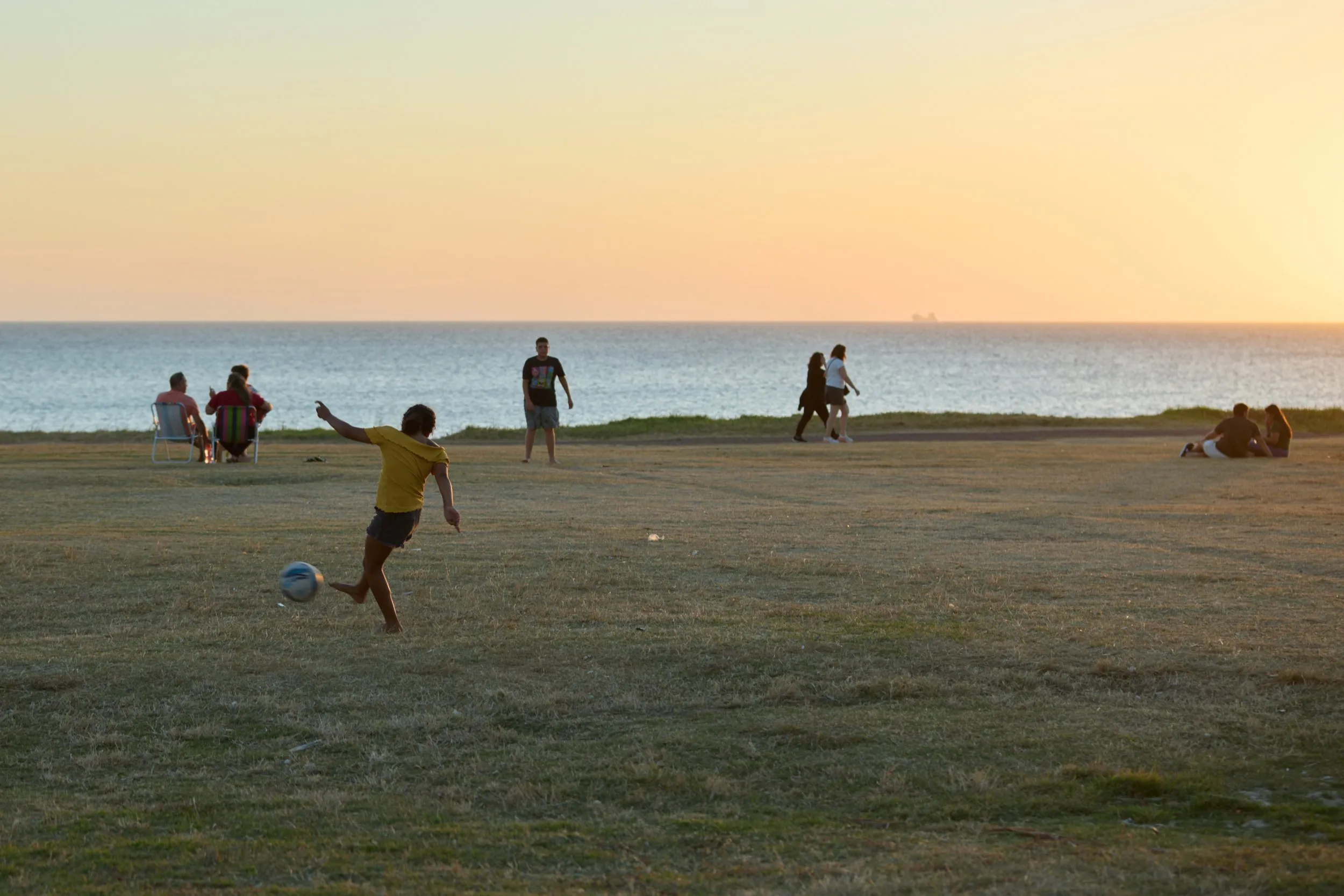 A football game on the grass of the Rambla de Punta Carretas, at sunset