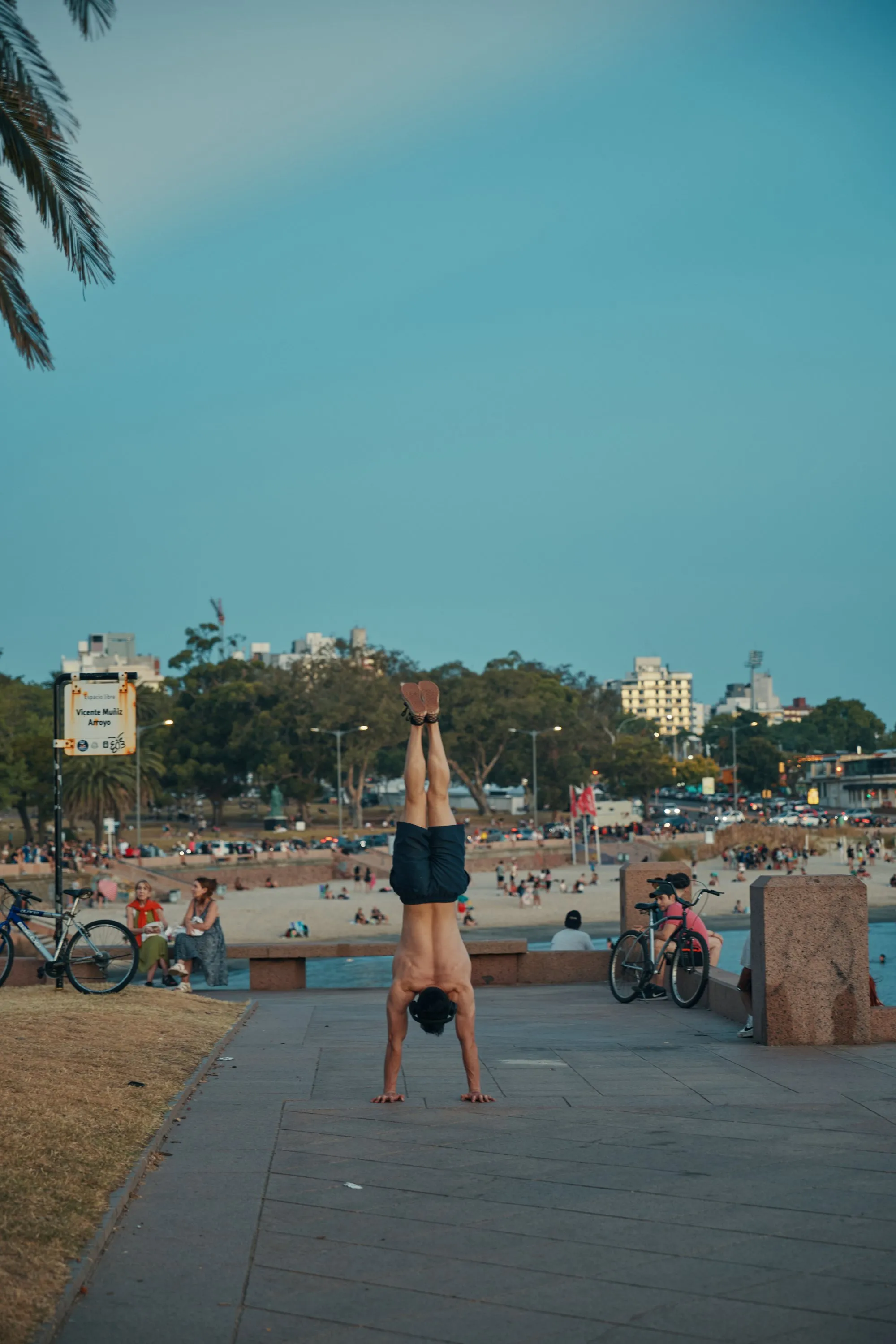 Someone doing a handstand on the wall of the Rambla Sur, the beach behind