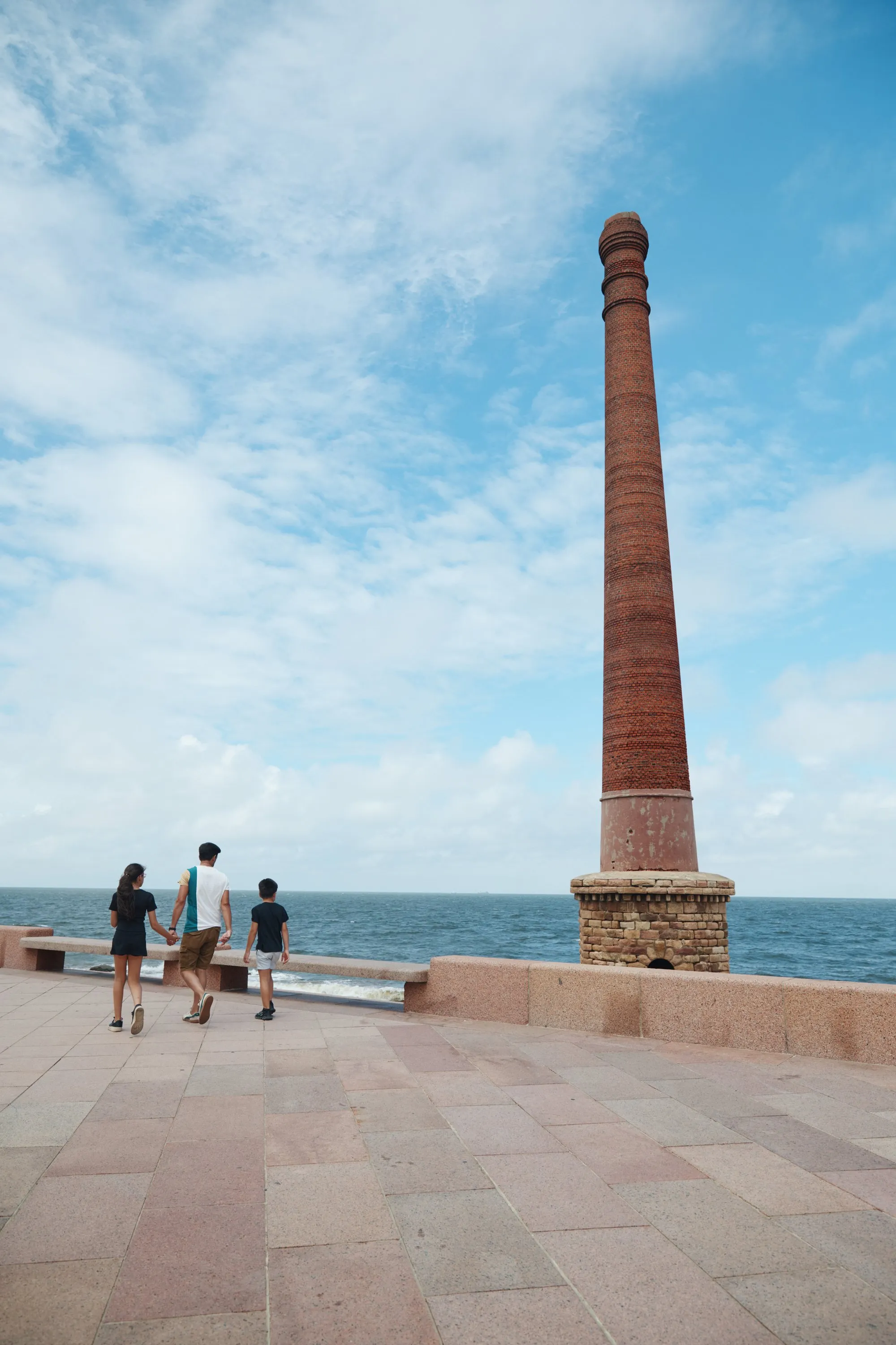 Three people looking out at the river beside an old brick chimney
