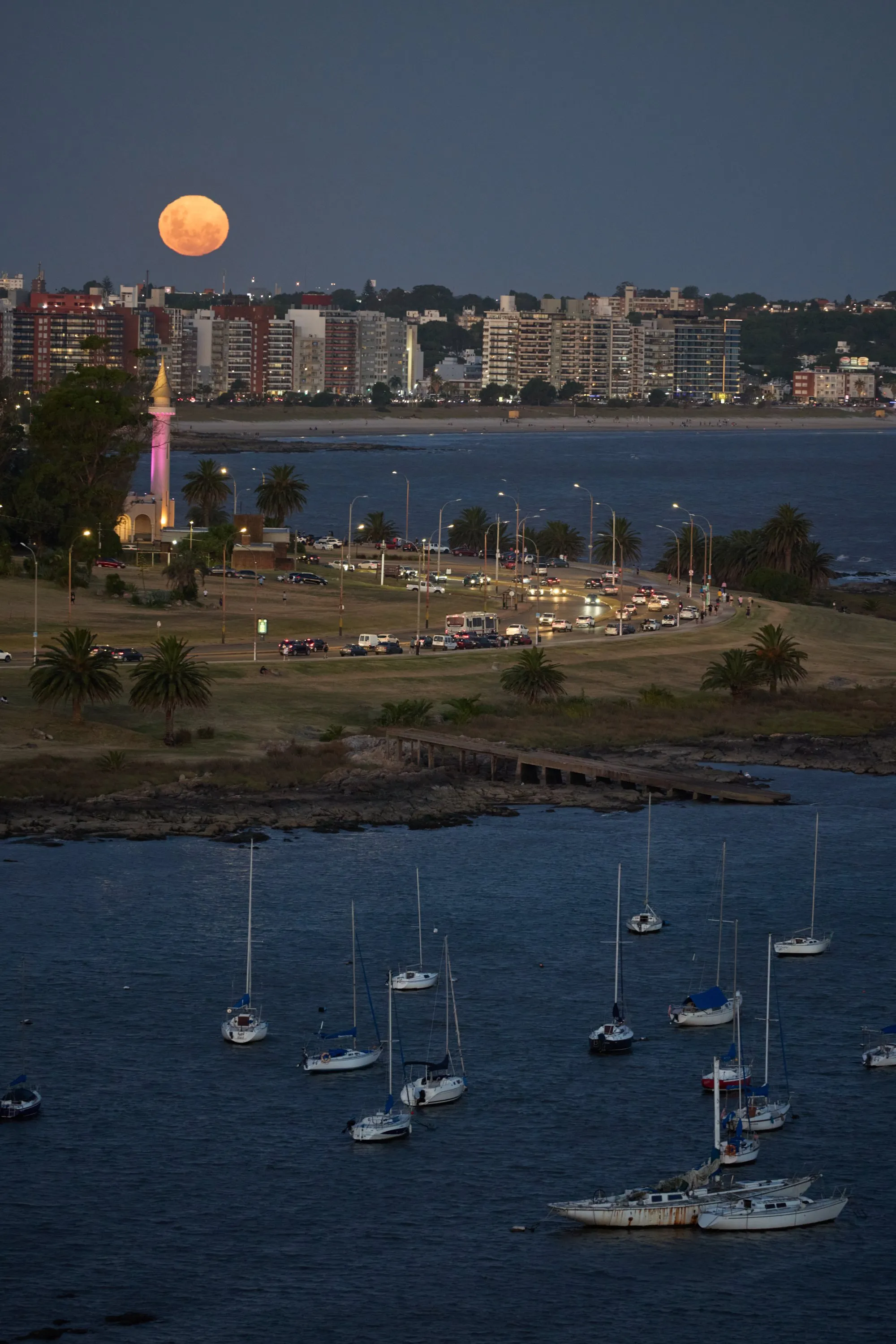 The Rambla of Montevideo by Buceo at nightfall, the lighthouse lit and traffic along the coast