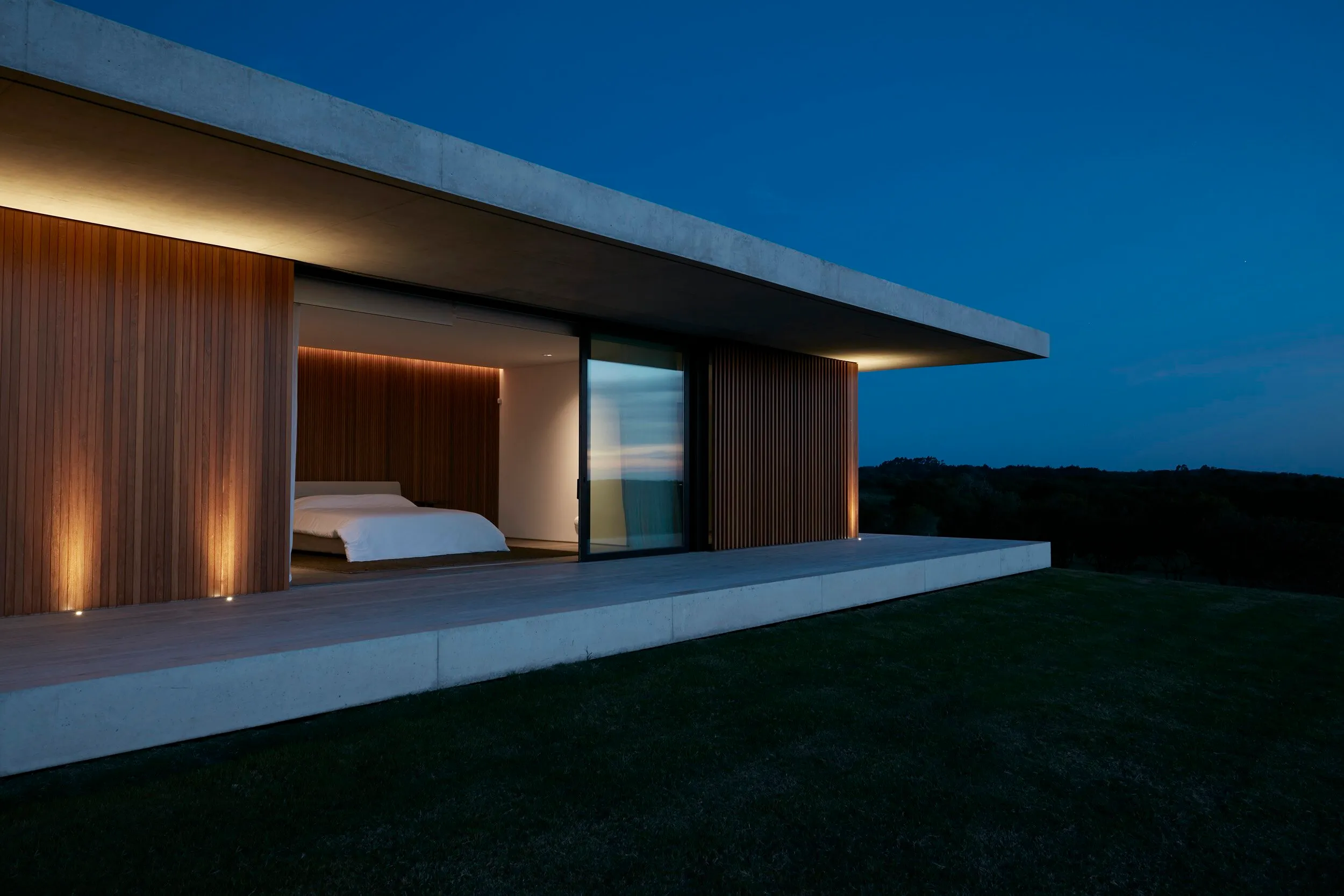 Modern house with a balcony and views of nature at night.