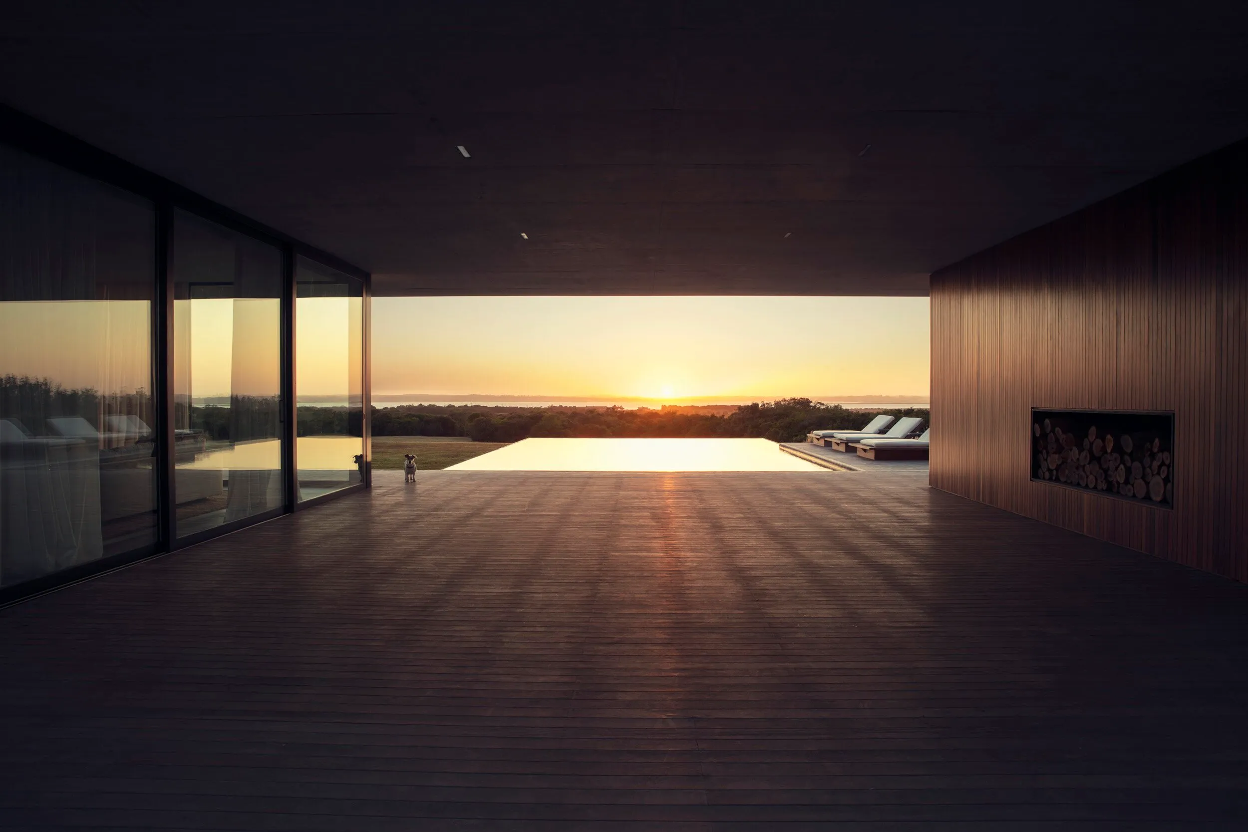 Modern terrace with sunset views, armchairs, and a built-in wood-burning fireplace.