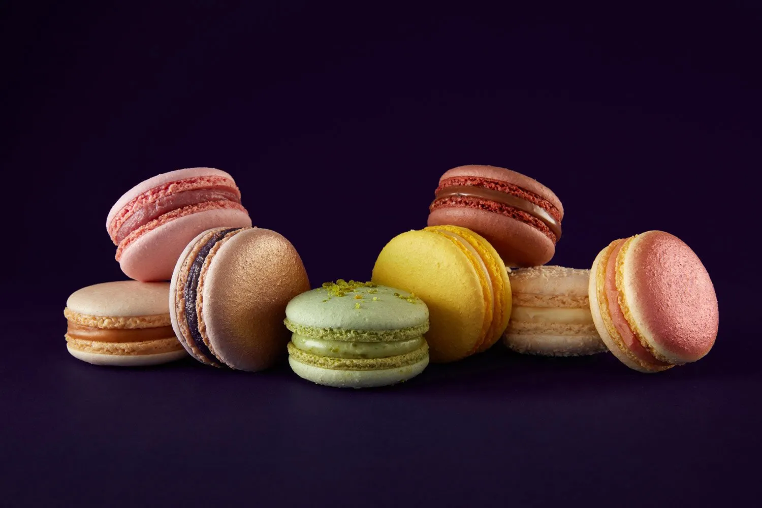 Macarons in different colors and flavors on a black background.