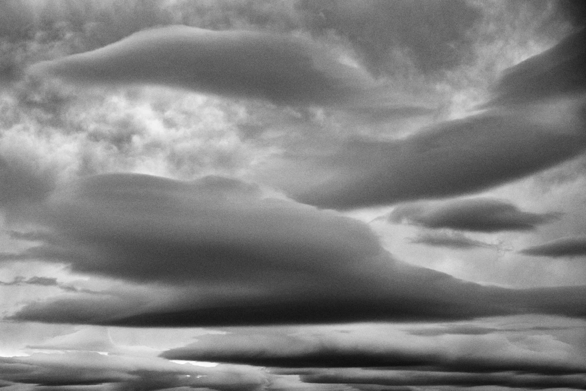 Lenticular clouds hanging like saucers, in black and white