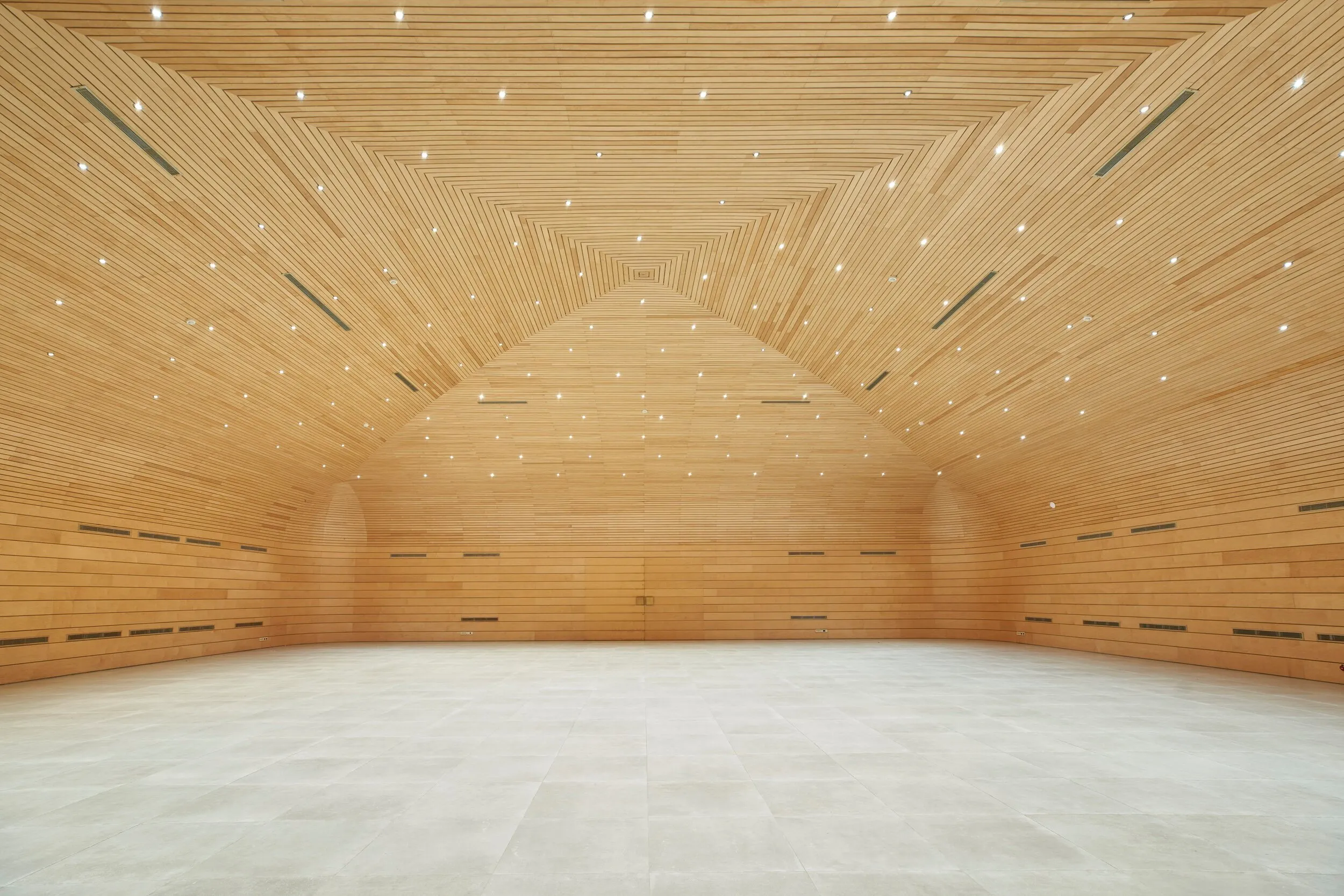 Spacious hall with wooden walls and ceiling and a light-colored tile floor.