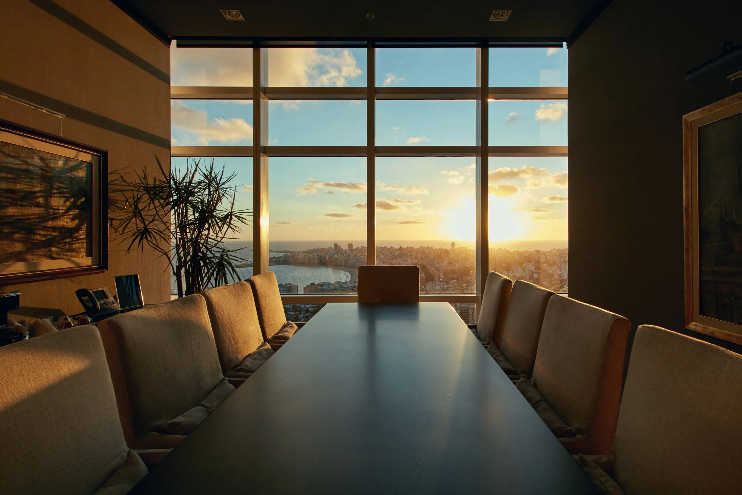 Meeting room with a large panoramic window showing a sunset over the city