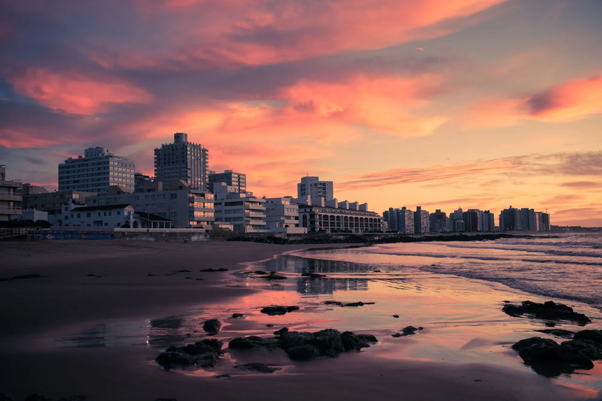 The buildings along the Punta del Este seafront at sunset, reflected in the wet sand