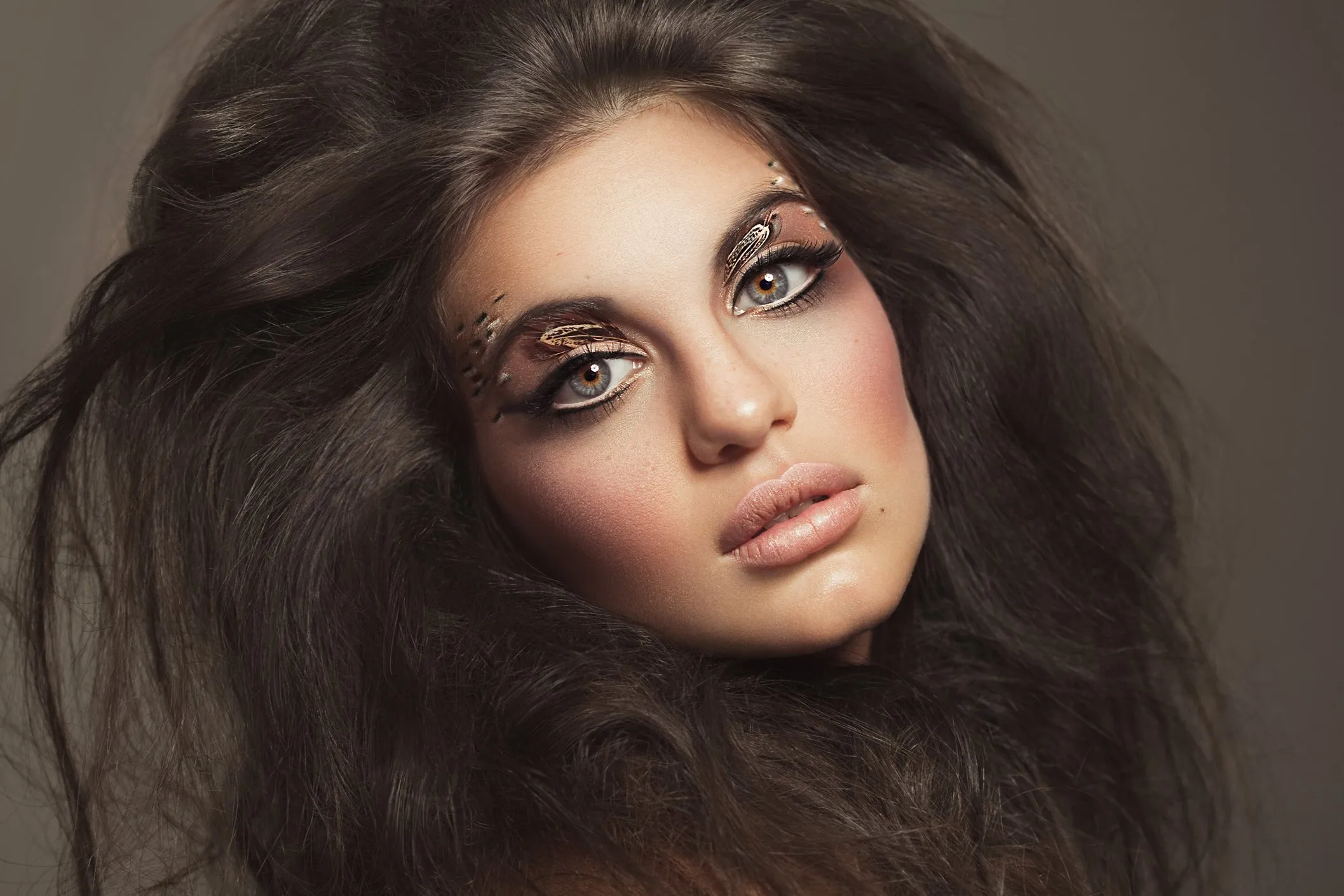 Portrait of a woman with artistic makeup and voluminous hair.