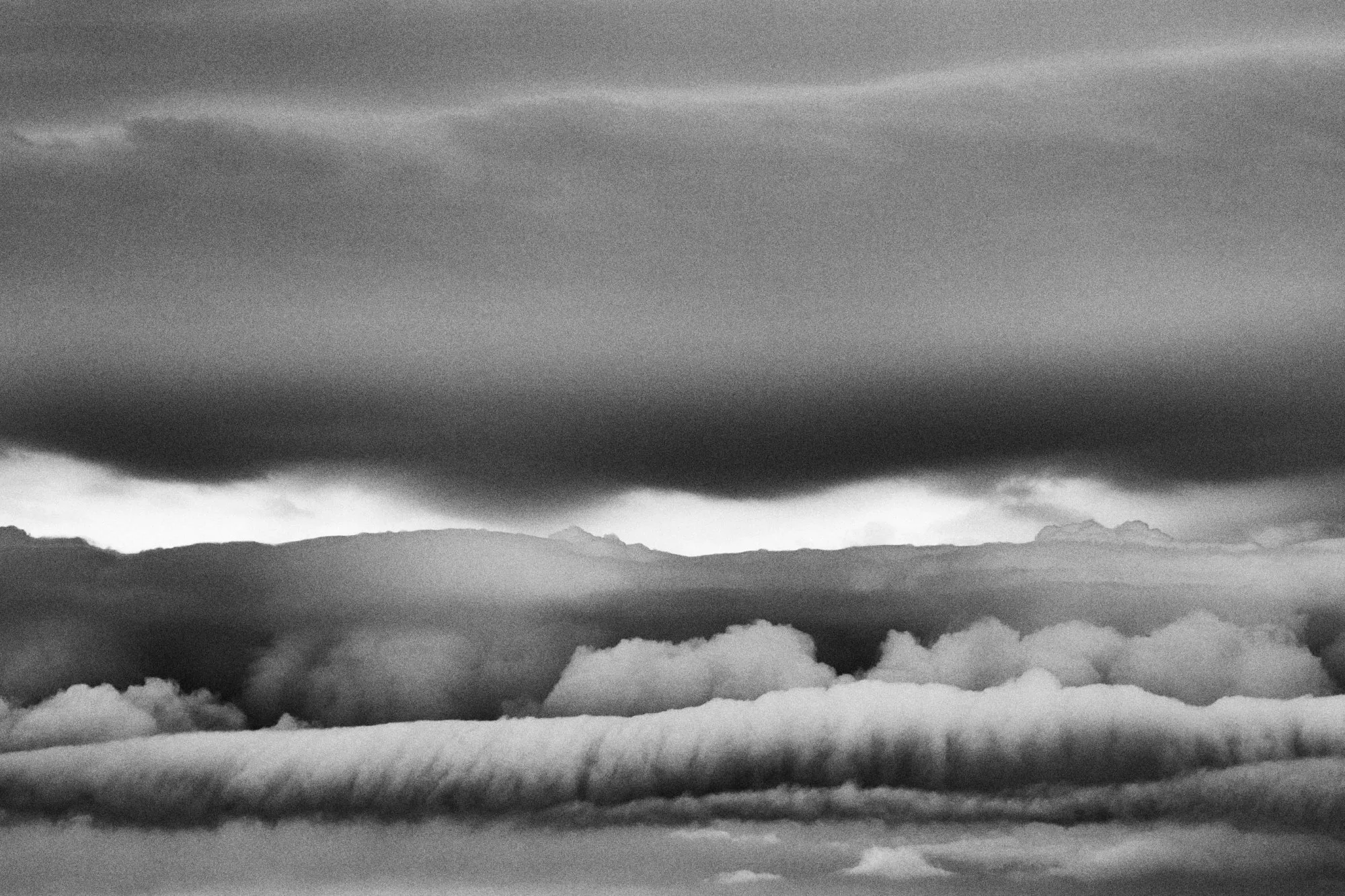 Layers of cloud, one long as a cigar above the horizon, in black and white
