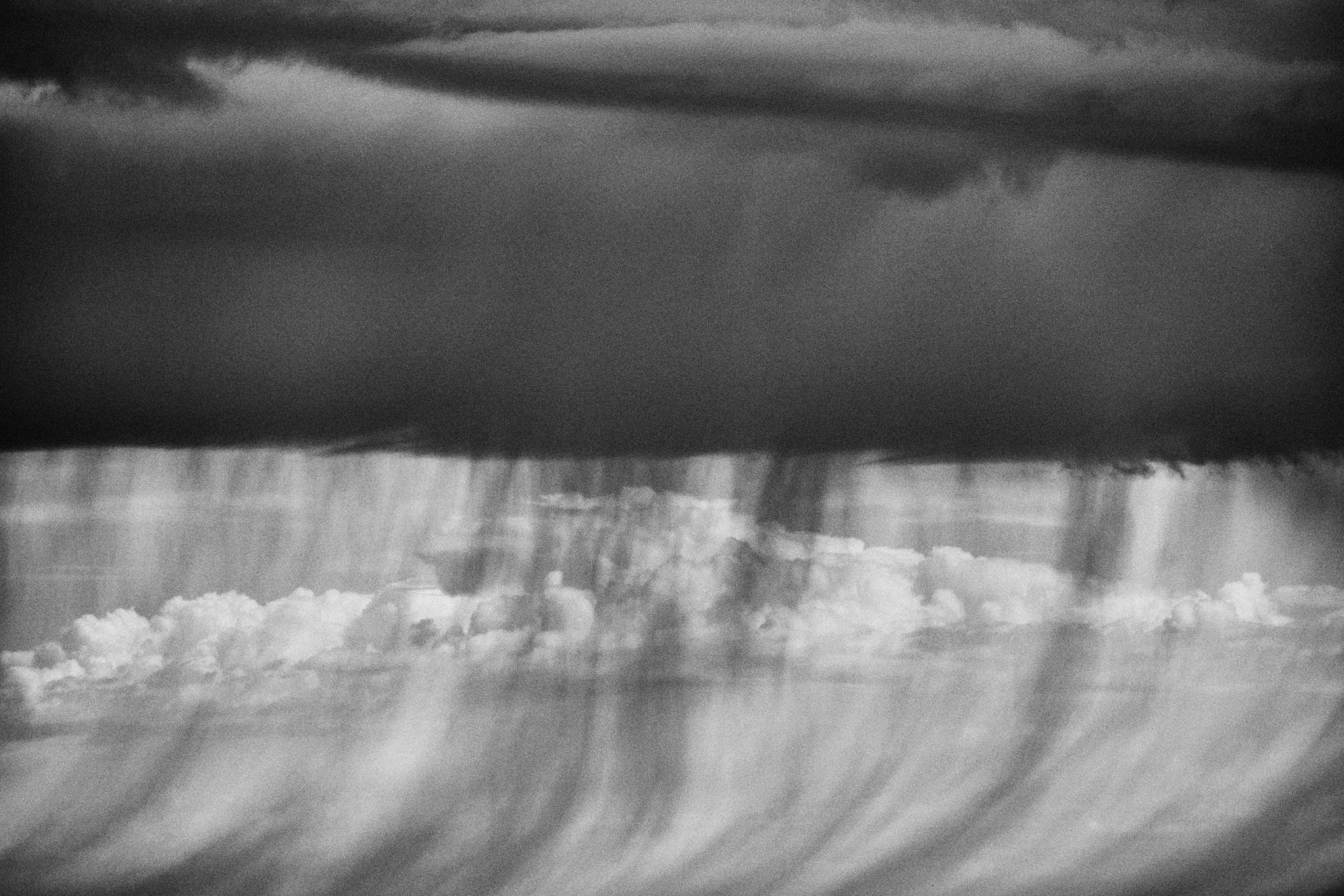Curtains of rain falling from a long cloud, in black and white